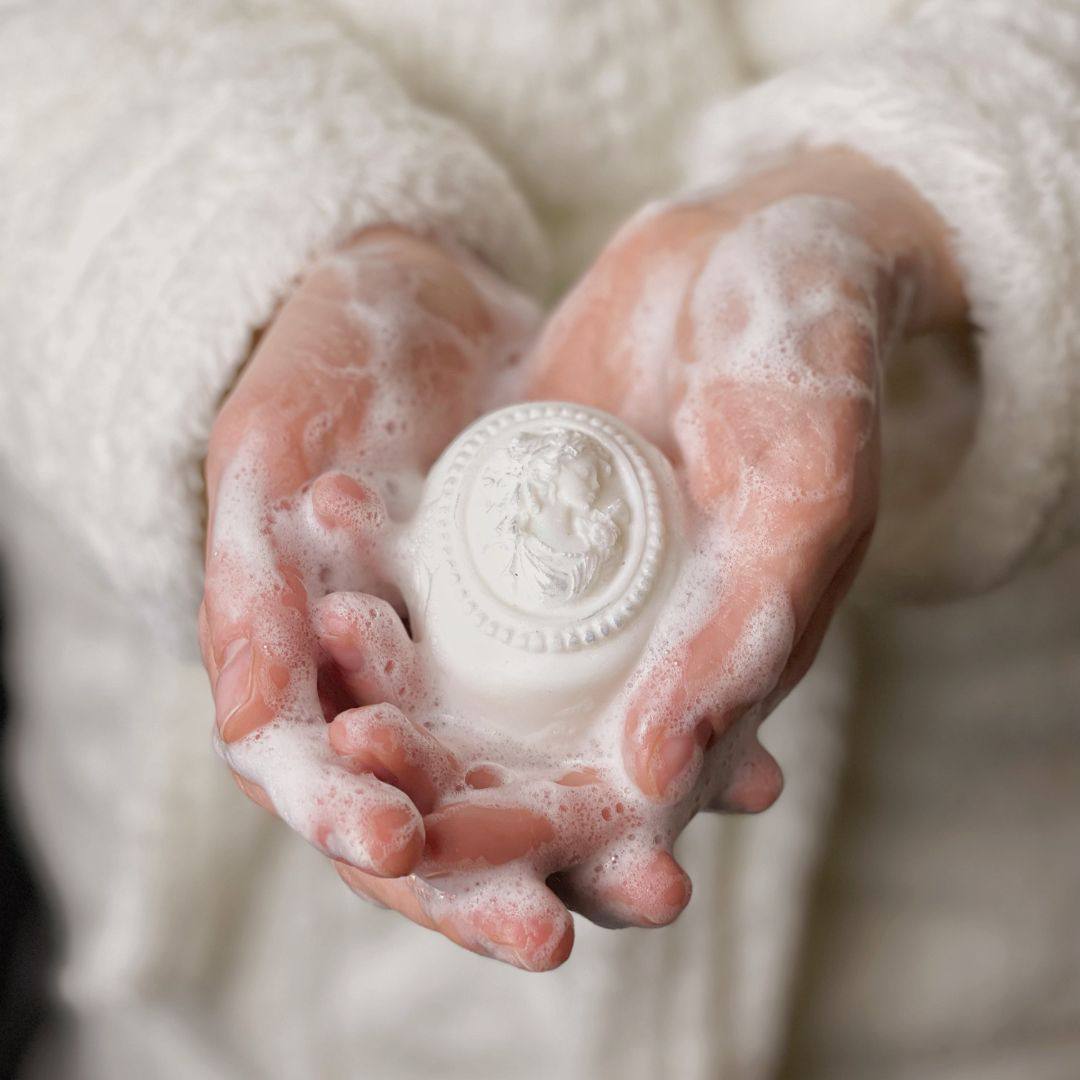 Hands holding round handmade soap covered in foam