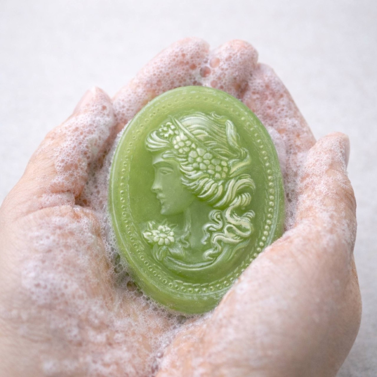 Green soap with decorative design on a black floral arrangement in a bathroom setting.